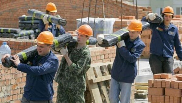 Робітники переносять матеріали на будівництві